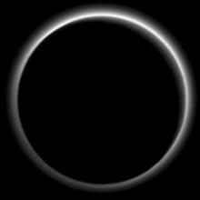 Dark side view of Pluto, a dwarf planet, with the Sun facing the other side of the dwarf planet. However, the light has created a halo-like effect on the dark side of the planet.