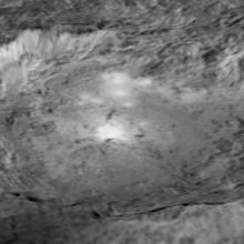 Black and white, close-up view of a large crater on Ceres, a dwarf planet. The crater has a shape similar to an oval.