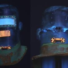 Side-by-side views of the Wiley Post pressure helmet, with the front visible on the left and the back visible on the right. Views are taken from ultraviolet light intended to discover corrosion products used on the helmet.