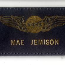 Black leather name tag with name "Mae Jemison" below NASA emblem with wings. The name and emblem are embossed in a golden color.