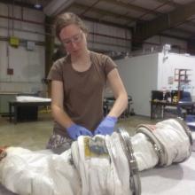 A white female Museum intern builds part of a spacesuit.