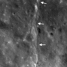 View of fault scarps, where land on one side has moved vertically, on the Moon. White arrows point out the fault line.