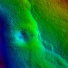 Colored topographic map of a portion of the Moon with a fault scarp visible as a line of dark greens (higher elevations) correspond with an immediate dip into lower elevations (highlighted in lighter greens).