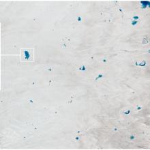 Satellite view of the Greenland ice sheet, where lakes of ice water have begun appearing. A panel shows a close-up view of one lake.