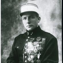 Portrait of Charles Nungesser, a French World War I pilot, as he sits wearing his military uniform with military decorations on his right chest.