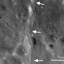 A set of fault scarps, or lines of rising crust on the Moon, which are pointed out using white arrows.