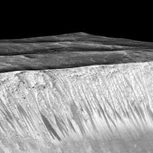 Darker-colored streak-like lines appear on the slope of a crater on Mars.