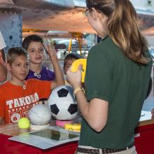 A Museum employee teaches multiple children about Mars as part of an astronaut game.