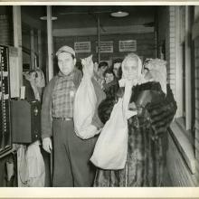 Multiple employees of an aeronautical corporation in the 1940s hold their bagged turkeys.