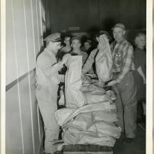 Employees of the Northwestern Aeronautical Corporation line up behind a stand of turkeys that are being given away.