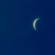 Daytime view of Venus, which is seen as a crescent shape.