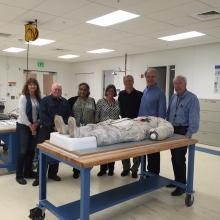 Alan Eustace, a record-holding altitude jumper, poses with members of the Museum's conservation staff on the side of Neil Armstrong's Apollo 11 spacesuit in the Museum's conservation laboratory.