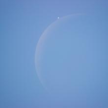 View of the daytime sky as the Moon is just about to block the view of Venus.