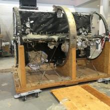 Side view of telescope mount spar, a telescopic object with a round-shaped base, prior to Museum restoration. The object is secutred to a wooden base and damage is seen to the black-colored material covering the center spar.