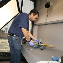 A Museum photographer moves an aircraft model prior to taking photos of the model.