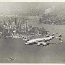 View of commercial aircraft in flight near a city.