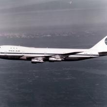 Black and white colored side view of aircraft with four engines and Pan Am Airways livery. Aircraft is in flight.