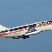 Side view of commercial aircraft in flight. Aircraft has at least two engines and red, black, and white PeoplExpress