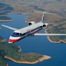 Front view of commercial jet in flight. The jet has two engines placed near the rear of the plane and white, blue, and red American Eagle livery.