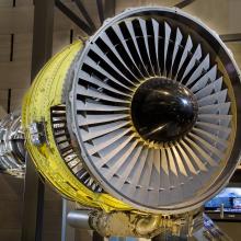 Front view of turbofan engine with large number of blades circling around a black, metal center.