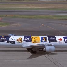 Side view of a commercial aircraft with multiple airline logos on the side of the aircraft.