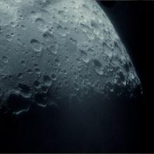 Partial view of the Moon with many craters visible.