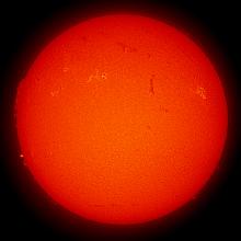 Disk view of the Sun with two visible sunspots and a large prominence of plasma rising from the Sun's surface on the left side of the disk.