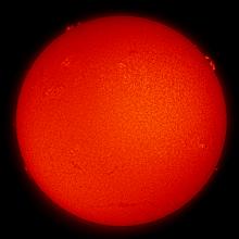 Disk view of the Sun with multiple sunspot clusters and filaments and prominences of plasma floating away from the surface of the Sun.