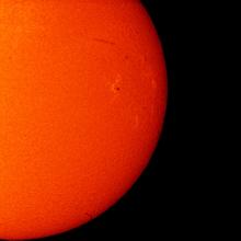 Partial disk view of the Sun featuring a sunspot on the right side of the Sun and a filament of plasma floating above the surface of the Sun.