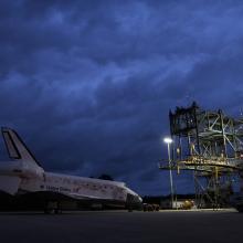 The Space Shuttle Discovery sits prior to being secured onto an aircraft via a large securing object known as a mate-demate device.