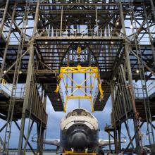 The Space Shuttle Discovery is placed under a securing device known as a mate-demate device prior to its arrival to the Udvar-Hazy Center.