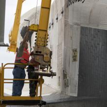 A lifting sling is placed on the Space Shuttle Discovery prior to the mate-demate device lifting the spacecraft onto a shuttle carrier aircraft.