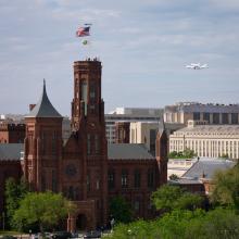 Space Shuttle Discovery, attached to an aircraft modified for shuttle transportation, flies near the Smithsonian Castle in Washington, D.C.