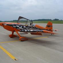 An orange aircraft with black and white painted accents and fixed landing gear.