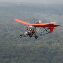 Red-winged ultralight aircraft with seating for two people.