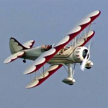 Side view of white and red biplane in flight with single engine.