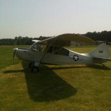 Side view of silver monoplane with single engine. A white and blue star emblem is painted behind the cockpit near the rear of the fuselage.