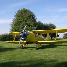 Frontal view of yellow biplane with single engine.