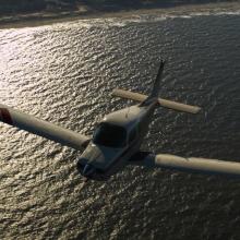 Front view of a monoplane with one engine flying above a body of water.