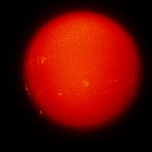 Disk view of the Sun's chromosphere with multiple sunspots and prominences of plasma rising from the chromosphere on the left side of the disk. Additional filaments of plasma floating above the chromosphere are visible on the bottom right quadrant of the disk.