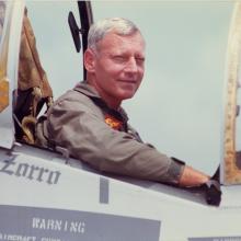 John R. Dailey, a white male general for the U.S. Marines, smiles from the cockpit of a plane.