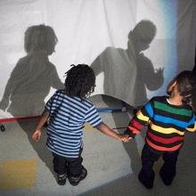 Two small children look at their shadows during a science activity.