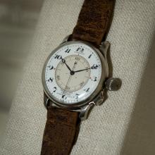 An analog watch with a brown leather watchband.