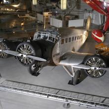 Silver-colored and black monoplane with three engines displayed in the museum.