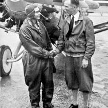 Thea Rasche, a white female pilot, holds hands with Clarence Chamberlin, a white male pilot.