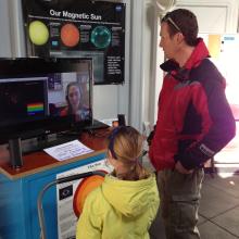 Two visitors speak with an astronomer through video chat in the Museum's observatory.