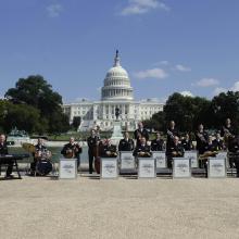 A group of jazz musicians in an ensemble stand outside the U.S. Capitol building.