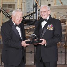 Joseph Sutter and Gen. Jack Dailey, both white men, pose for a photo as Joseph Sutter accepts a trophy.