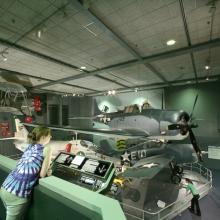 A visitor leans to look closer at an artifact in the Sea-Air Operations Gallery.