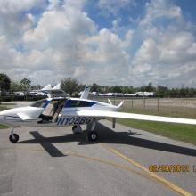 Side view of white aircraft with long back wings and a rear single engine. The registration number "N108BG" is painted in blue under the wing.